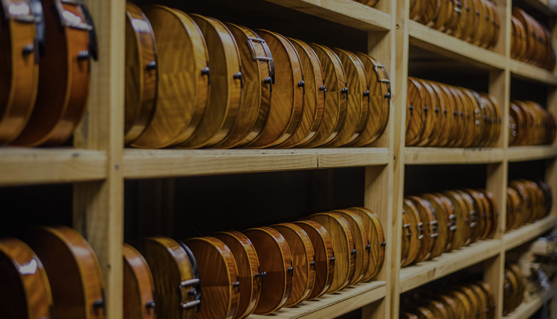 Rows of finished violins standing on wooden shelves in the KG warehouse.